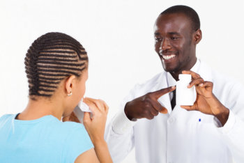 pharmacist pointing at a bottle of medicine in front of a woman